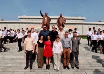 A group of tourists pose in front of the Mansudae statues of Kim Il Sung and Kim Jong Il.