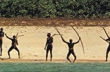 A shot of the North Sentinel Island tribe waving their bows from the beach